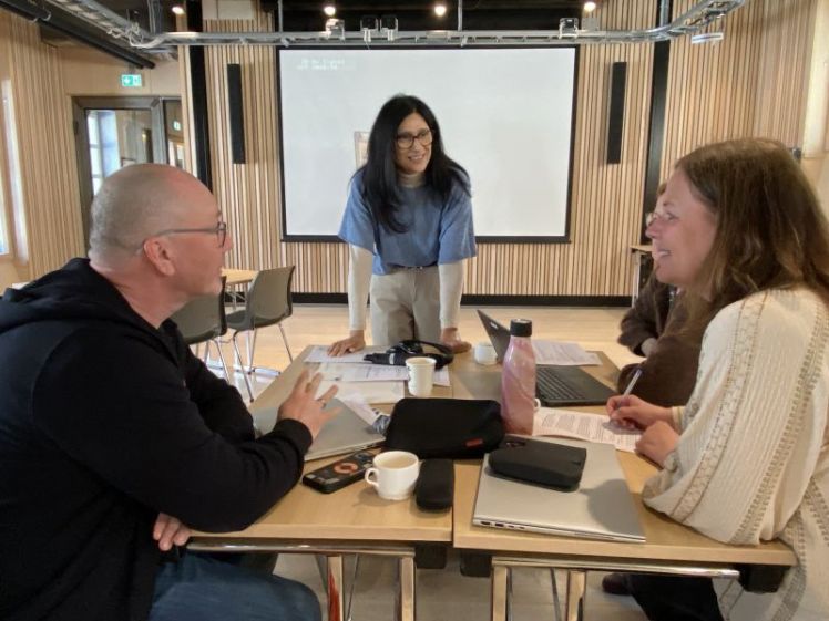 Tre personer rundt et bord jobber og diskuterer